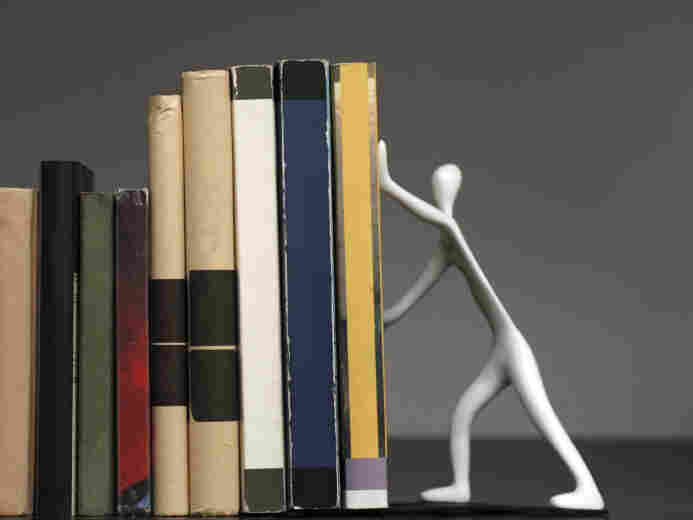 A bookend shaped like a person, holding up a row of books