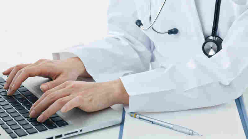 A doctor types at a computer.