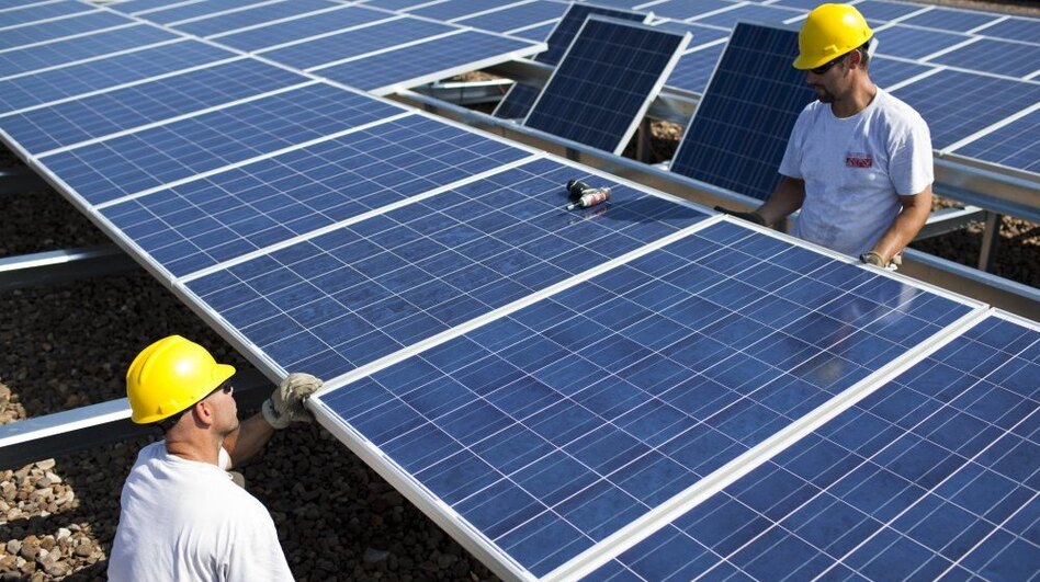 Contractors with SunEdison install more than 1,000 Chinese-made solar panels on top of a Kohl's Department Store in Hamilton Township, N.J., in 2010. Energy generated by the solar system will cut the store's usage, on average, by 25 to 30 percent. (Robert Nickelsberg/Getty Images)