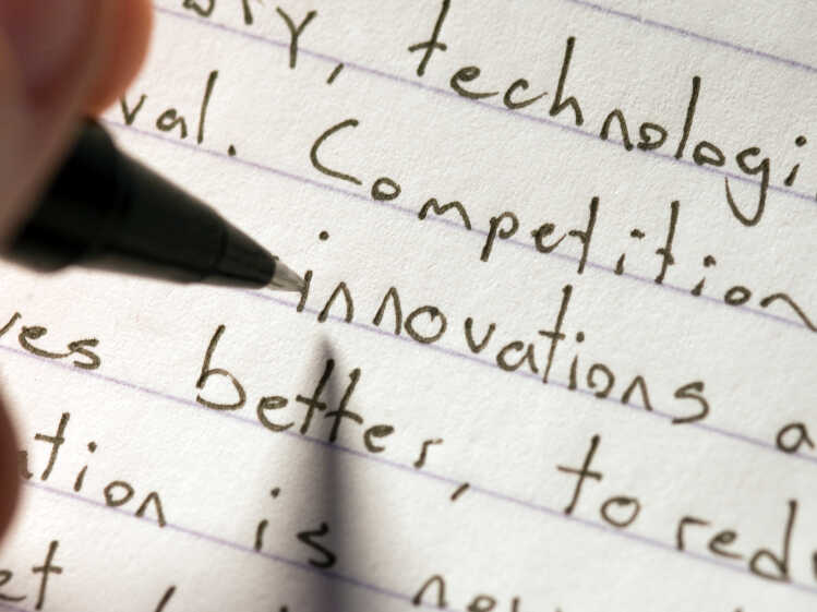 A person writes an essay by hand.