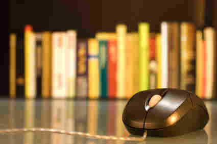 A computer mouse in front of a shelf of books.