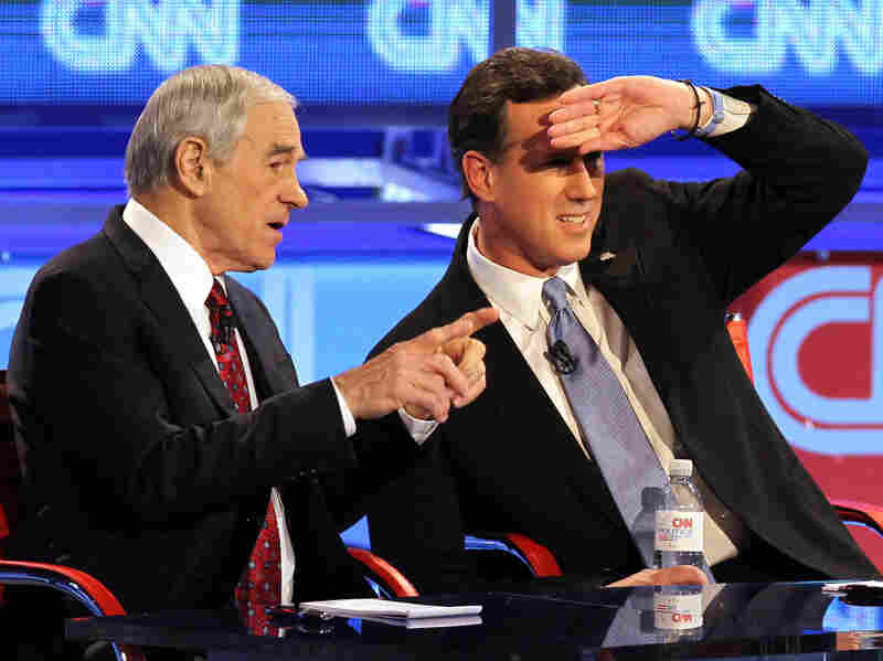 Republican presidential candidates (L-R) U.S. Rep. Ron Paul (R-TX), and former U.S. Sen. Rick Santorum talk during a commercial break as they participate in a debate sponsored by CNN and the Republican Party of Arizona at the Mesa Arts Center February 22, 2012 in Mesa, Arizona.