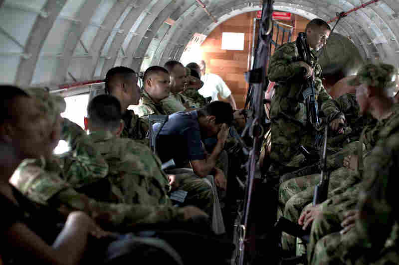 Colombian infantry troops and civilian passengers rest during a flight.