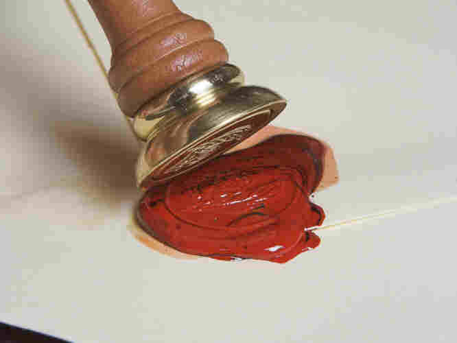 Envelope being closed and sealed with hot red wax