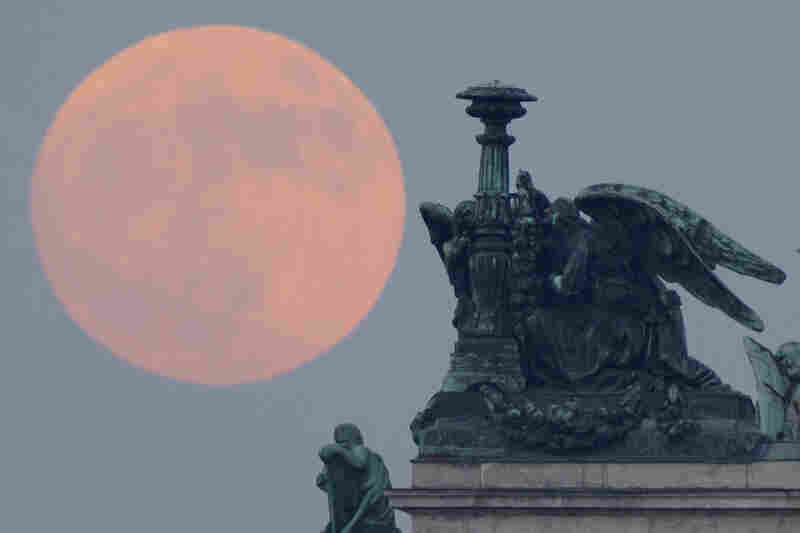 The full moon rises behind statues of angels fixed at the St. Isaak's Cathedral in St.Petersburg, Russia. 