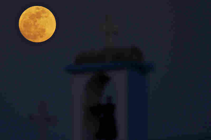 The full moon rises behind a steeple with cross of Ayia Thekla (Saint Thekla) Christian Orthodox church near coastal resort of Ayia Napa, Cyprus. 