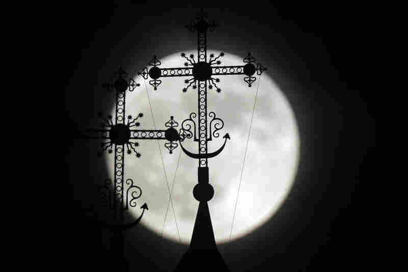 The full moon rises behind a steeple with crosses of an Orthodox church in the town of Novogrudok, Belarus. 
