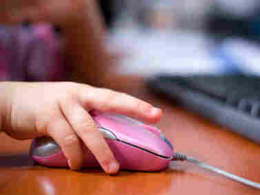 Child's hand on a pink computer mouse.