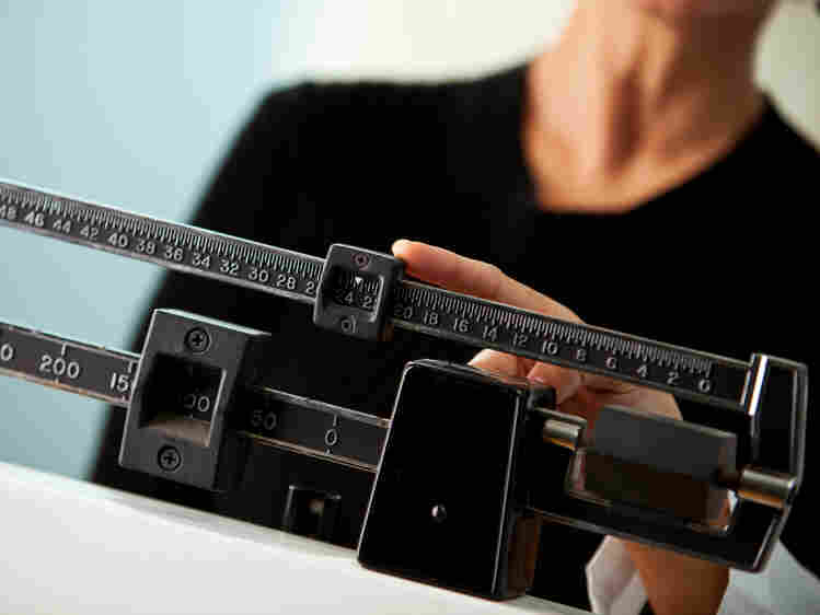 A woman checks her weight at the doctor's office.