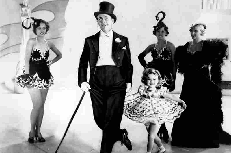 Temple curtsies in a promotional photo for the musical Stand Up and Cheer with James Dunn in 1934.