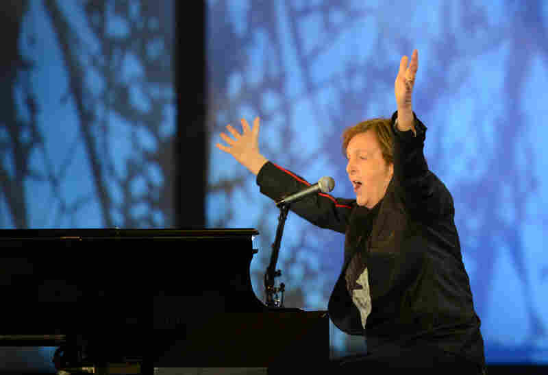 British musician Paul McCartney raises his arms as he sings at the end of the opening ceremony.