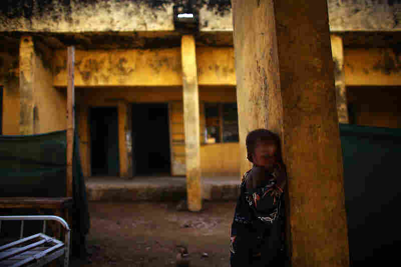 Aishsa Yusufa stands against a pillar outside the Doctors Without Borders ward in Anka, Nigeria. The 4-year-old girl is enrolled in a program at the clinic to treat her for high levels of lead.