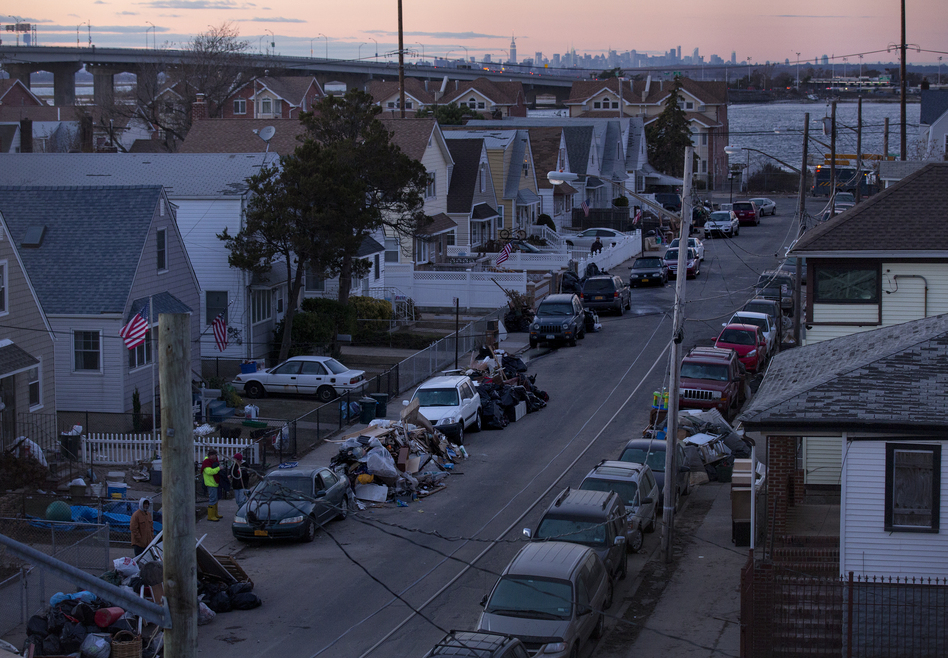 Debris lay in front of homes in a Rockaway neighborhood of the borough of Queens, New York, on Monday. The Manhattan skyline is seen in the background. (AP Photo/Craig Ruttle)