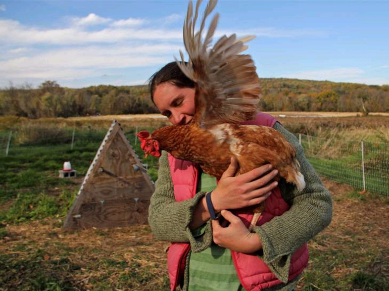 Chris Costa and one of her chickens on her farm in Downingtown, Pa. Costa and her partner, T.J., found the land for this farm through a sustainable agriculture program. (Emma Lee/WHYY)