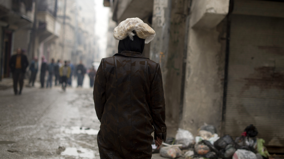 A Syrian woman carries a ration of bread on her head in the northern city of Aleppo. The Syrian opposition now runs local councils in many cities, particularly in the north. They often face major challenges in providing basics likes food, water and electricity. (Odd Anderson/AFP/Getty Images)
