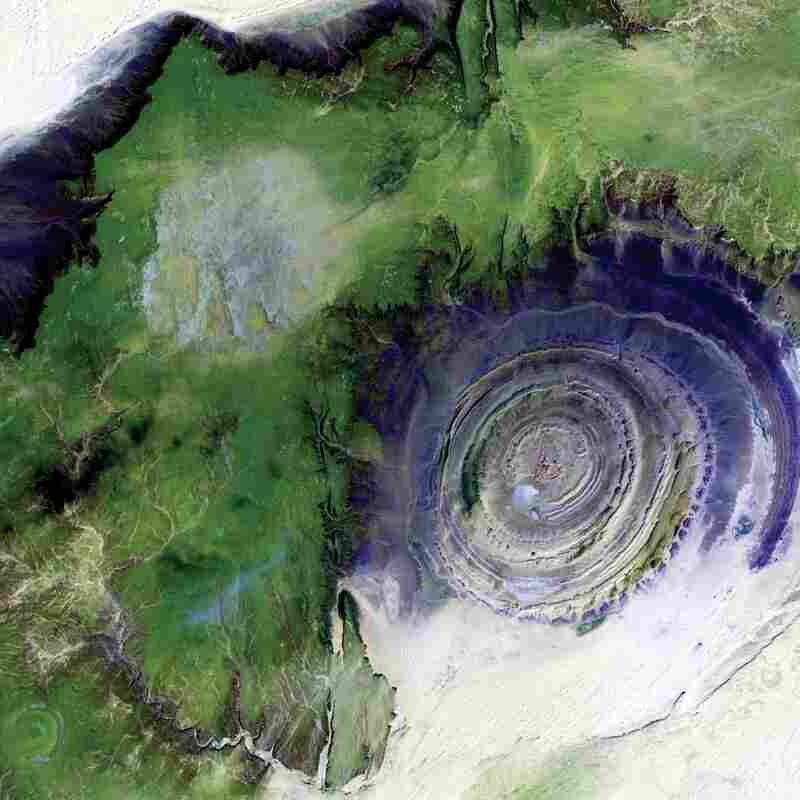 Richat Structure, Mauritania, 2001The 31-mile-wide bull's-eye in the western Sahara is a landmark for astronauts. The structure formed when a volcanic dome hardened and gradually eroded, exposing the onion-like layers of rock. Desert sands appear white and pale yellow at the corners; less sandy, rocky areas are green; and volcanic rocks are blue.