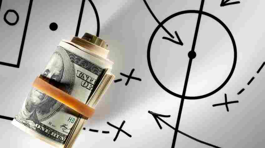 Roll of dollars on a blackboard with football strategy planning.