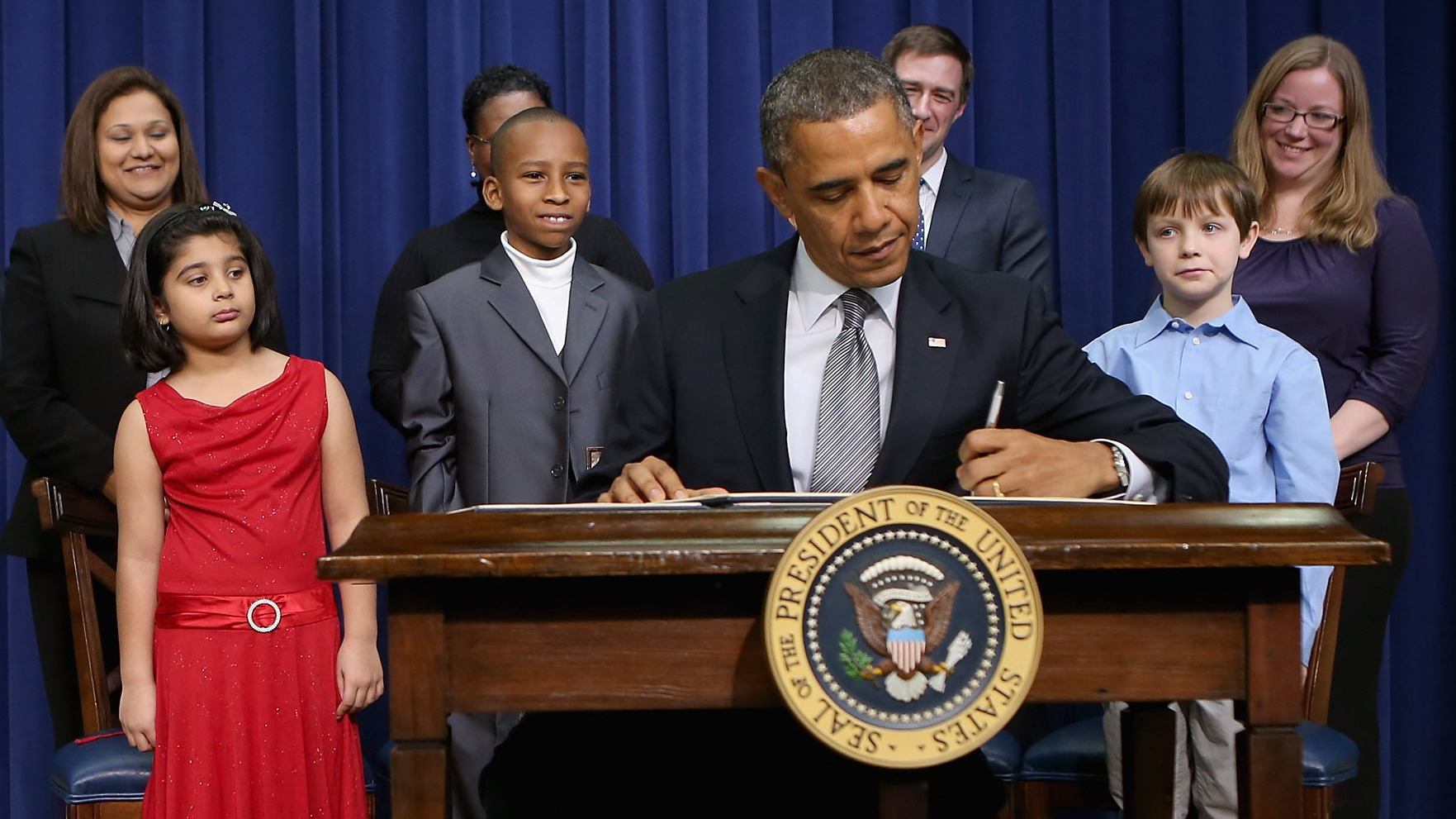 President Obama signs a series of executive orders Wednesday about the administration's gun law proposals as Vice President Biden and children who wrote letters to the White House about gun violence look on. (Getty Images)
