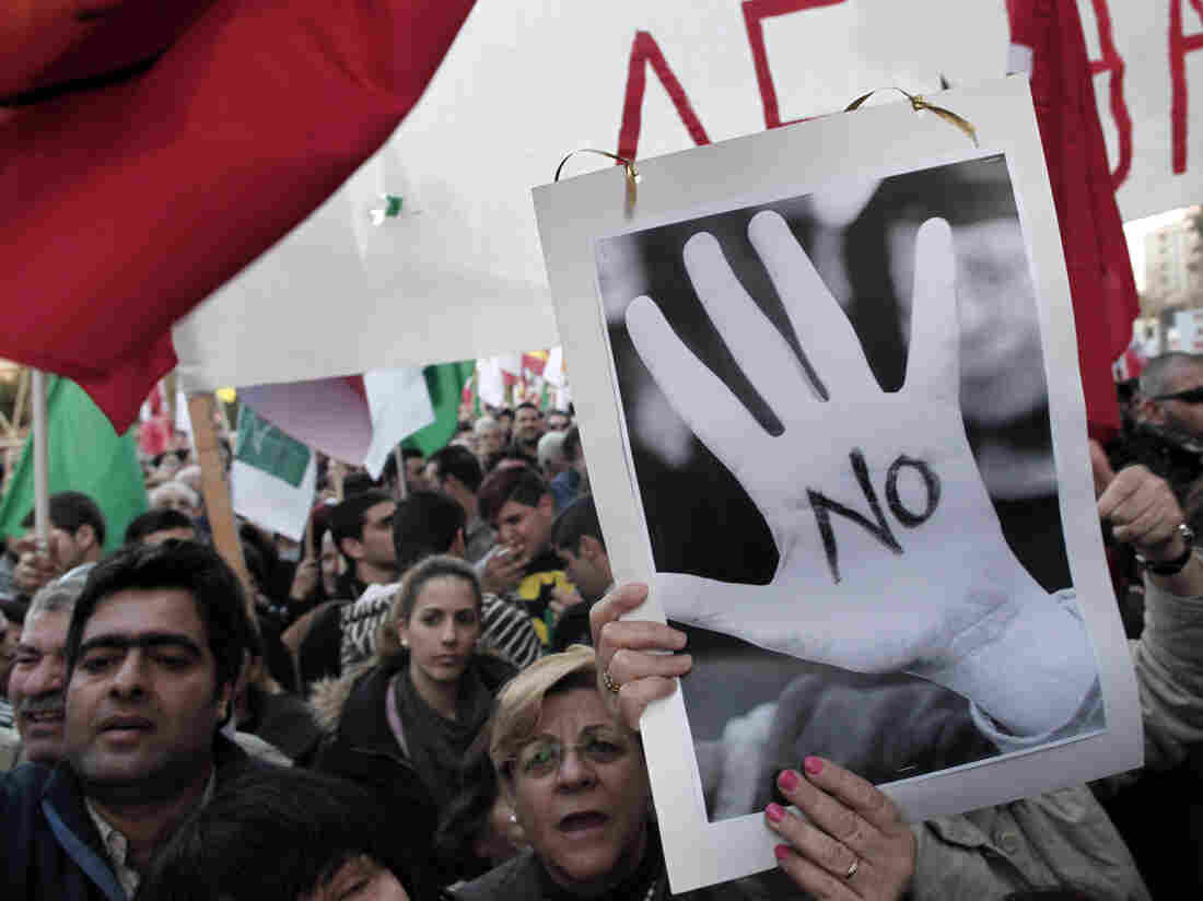 Protesters chant slogans outside the Cypriot parliament in central Nicosia, Tuesday, March 19, 2013.