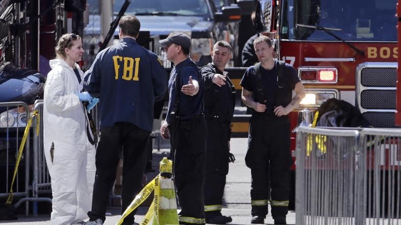 Boston firefighters talk with FBI agents and a crime scene photographer Tuesday at the scene of the Boston Marathon explosions. (Charles Krupa/AP)