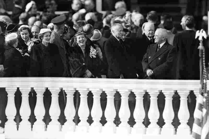 Outgoing President Harry Truman, at right, and new first lady Mamie Eisenhower, left, appear to be sharing a joke on presidential inauguration stand in Washington, Jan. 20, 1953, but ex-president Herbert Hoover, behind Truman, takes a serious view of the situation.