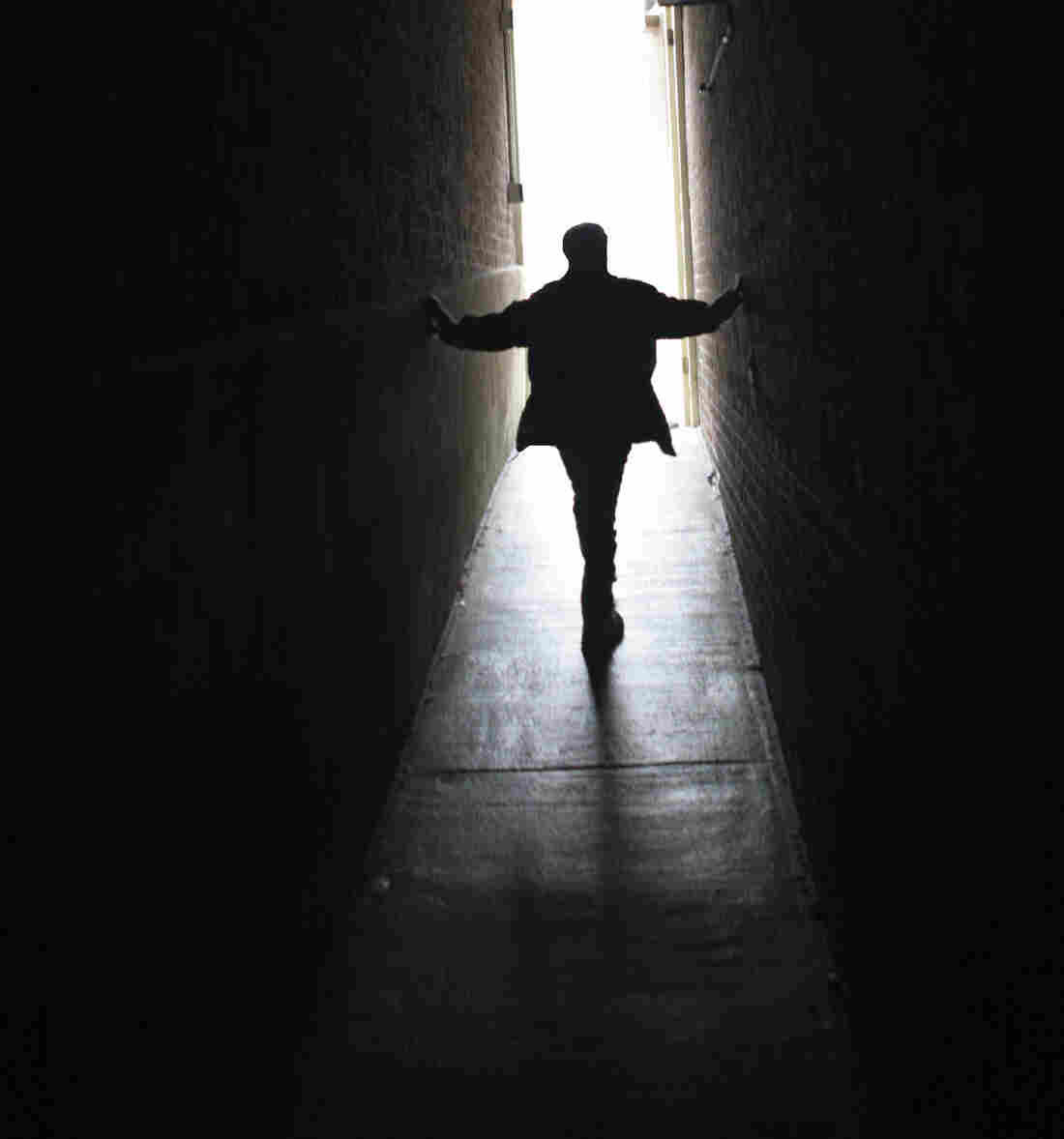 A person walks up a ramp toward a brightly lit door.