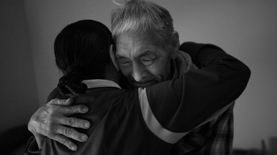 Frankie Kuzuguk, 82, gets a hug from his daughter Marilyn Kuzuguk at Quyanna Care Center in Nome, Alaska, after receiving an official honorable discharge and a distinguished service coin from visiting Veterans Affairs officials. The VA is still tracking down the few surviving members of the World War II Alaska Territorial Guard or delivering benefits to their next of kin. (David Gilkey/NPR )
