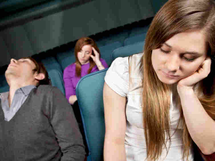 Bored people in a movie theater falling asleep.