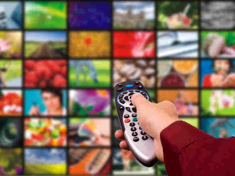 A hand with a remote looking at many screens.