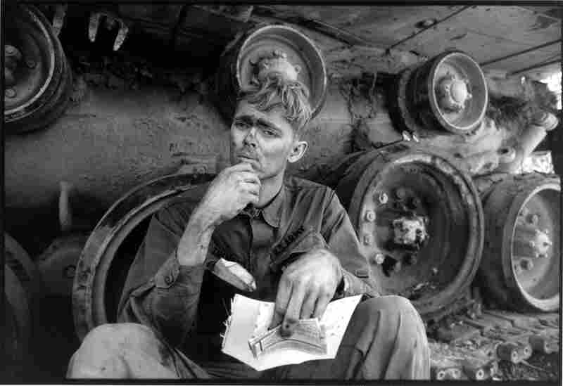 An American soldier reads a letter from home while taking a break from repairing a tank tread in Lang Vei, Vietnam, 1971.