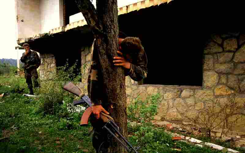 A Bosnian soldier stands on what is believed to be a mass grave outside his destroyed home. He was the sole survivor of a massacre that left 69 people dead, including his family, 1995.