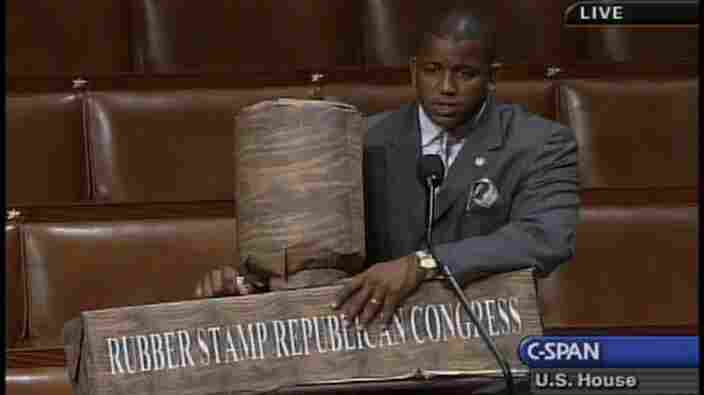 Former Rep. Kendrick Meek (D-Fla.) holds a "rubber stamp" prop created mostly out of paper.