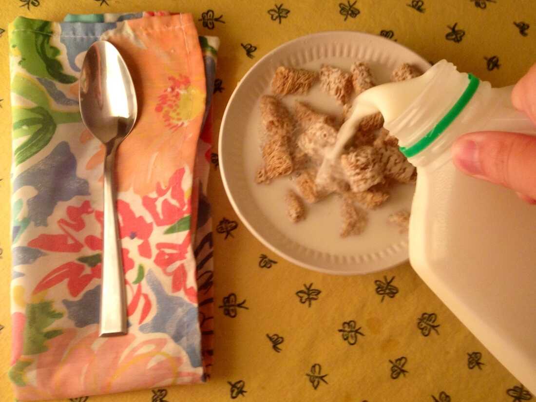 Pouring milk on cereal.