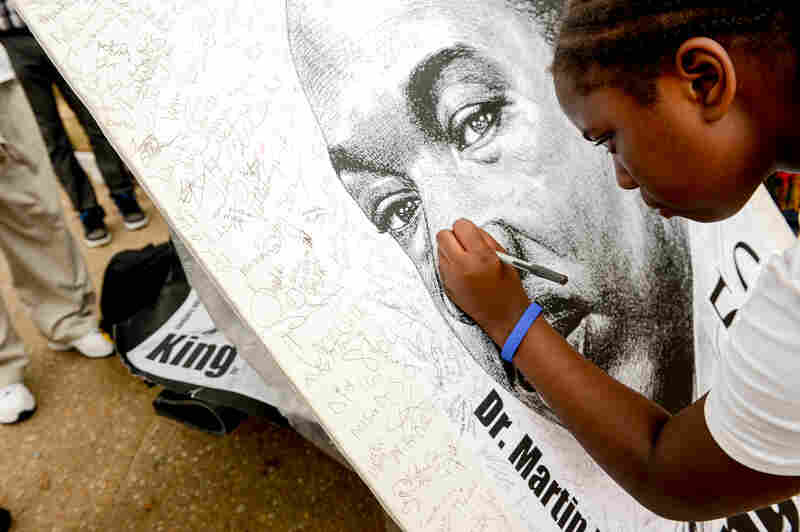 Shayna Mason, 11, signs a poster of King following a march down Pennsylvania Avenue.       