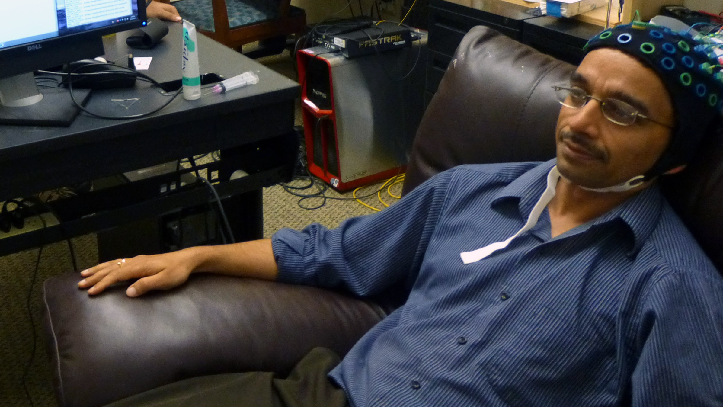 Acting as a &quot;sender,&quot; brain researcher <a href=&quot;http://www.cs.washington.edu/people/faculty/rao/&quot;>Rajesh Rao</a> watches a video game and waits for the time to hit the &quot;fire&quot; button. But he'll only think about doing that — the impulse was carried out by someone in another building, in a recent test of brain-to-brain communication. (University of Washington)