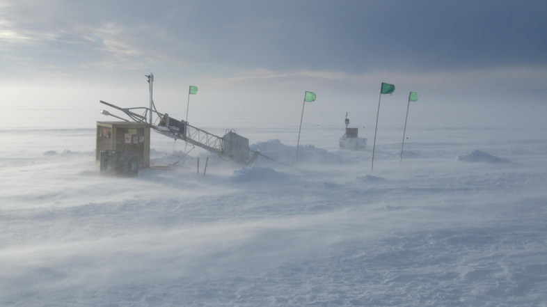 The surface tower at a drill site, under construction during blistering Antarctic winds. Data from instruments, deployed through 450 meters of ice, is transmitted from the tower by satellite back to the Naval Postgraduate School. (Image courtesy of Tim Stanton)