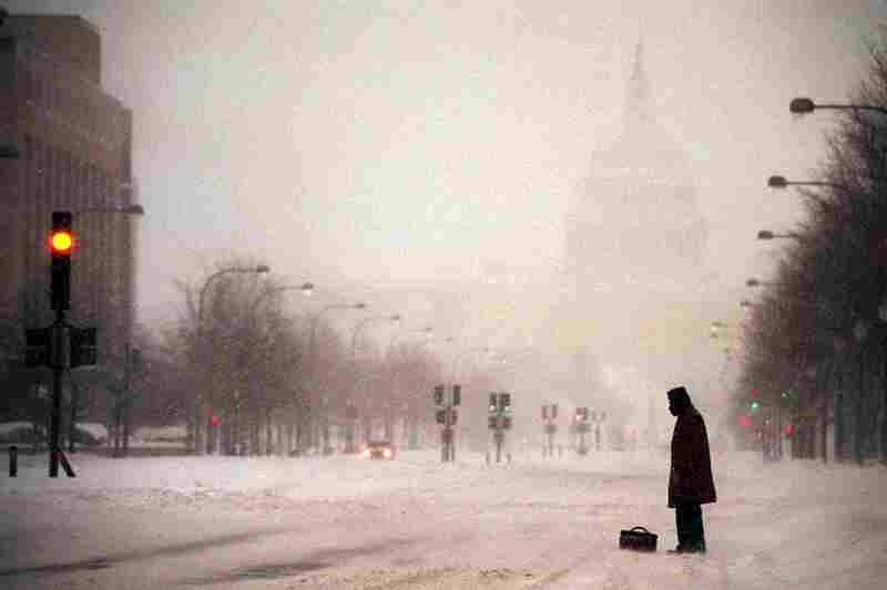 With the Capitol in the background, a lone pedestrian waits for a ride on Pennsylvania Avenue as snow falls on Jan. 8. That winter storm paralyzed the city and closed the federal government, just two days after it reopened.