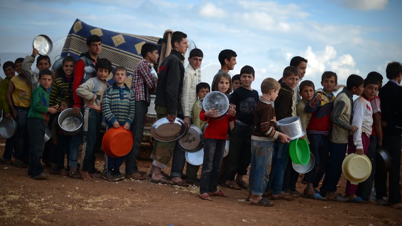 Syrian youths line up for food distribution in the Maiber al-Salam refugee camp in northern Syria, near the border with Turkey. The U.S. government has provided more than $1.5 billion in aid to Syrians since the uprising began in 2011. (Dimitar Dilkoff/AFP/Getty Images)
