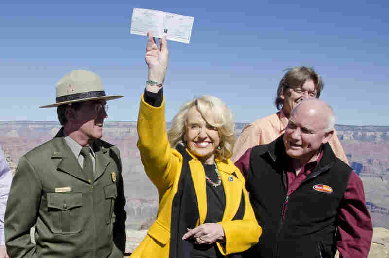 Arizona Gov. Jan Brewer holds a check for $426,500, presented to her by the town of Tusayan, Ariz., as partial payment to open Grand Canyon National Park. The National Park Service announced that it entered into an agreement with the state of Arizona that would allow the park to re-open and temporarily operate during the shutdown.