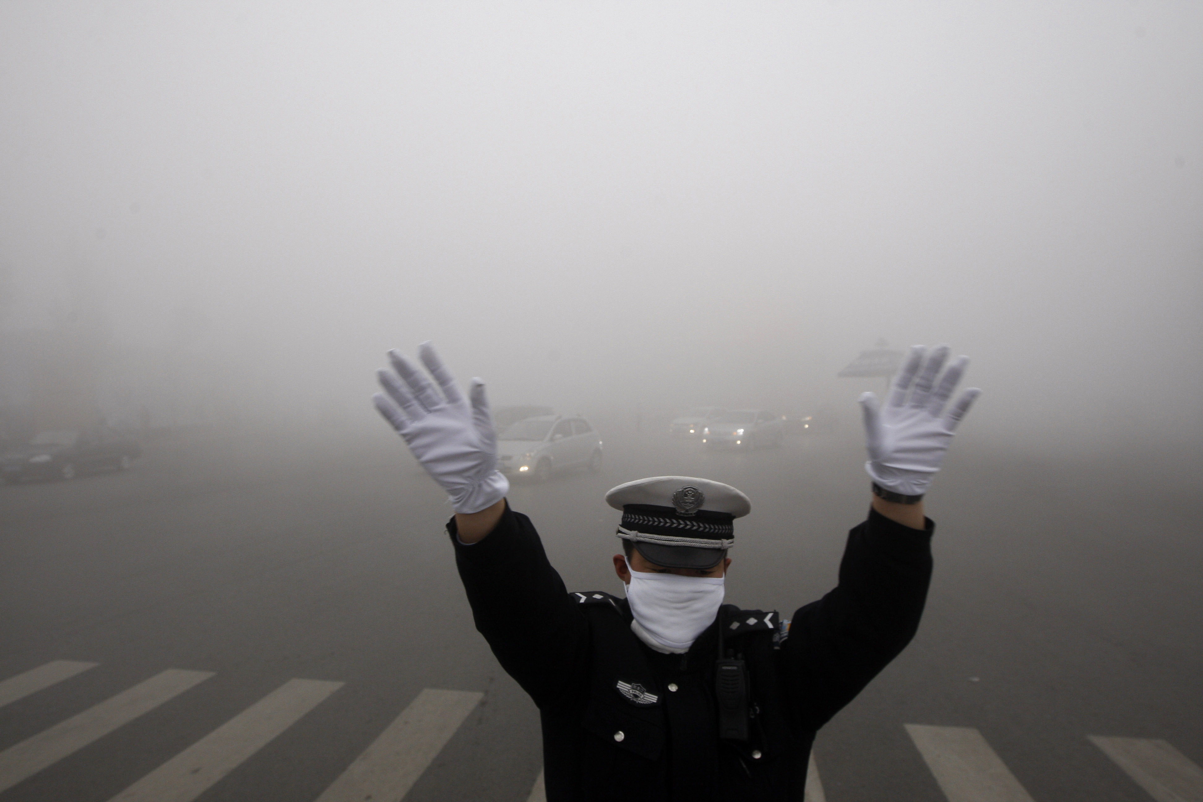 A policeman gestures as he works on a street in heavy smog in Harbin, northeast China's Heilongjiang province, on Monday. (AFP/Getty Images)