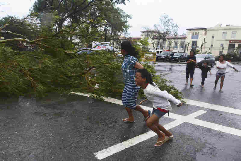 Residents rush to safety past a fallen tree as strong winds from the typhoon hit Cebu City.