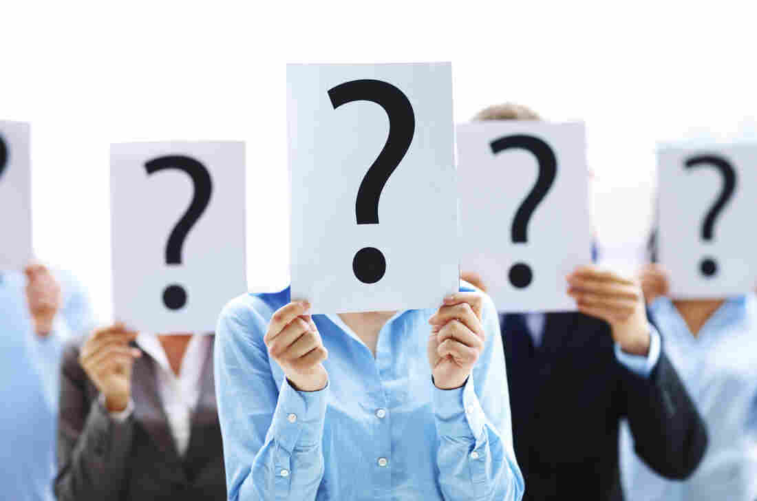 A group of people holding up question marks in front of their faces.
