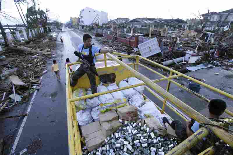 Filipino policemen secure a truck load of relief goods in the typhoon devastated city of Tacloban, on the eastern Filipino island of Leyte on Tuesday. Aid workers and relief supplies were being poured into eastern provinces hit by Typhoon Haiyan, which aid agencies and officials estimated has left thousands dead and staggering destruction in its wake.