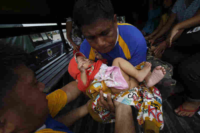 A child, one of the survivors who was evacuated from the disaster zone, is carried into a military truck with her family after they arrive via at Villamor Air Base in Manila. Rescue workers tried to reach towns and villages in the central Philippines on Tuesday that were cut off by the typhoon.