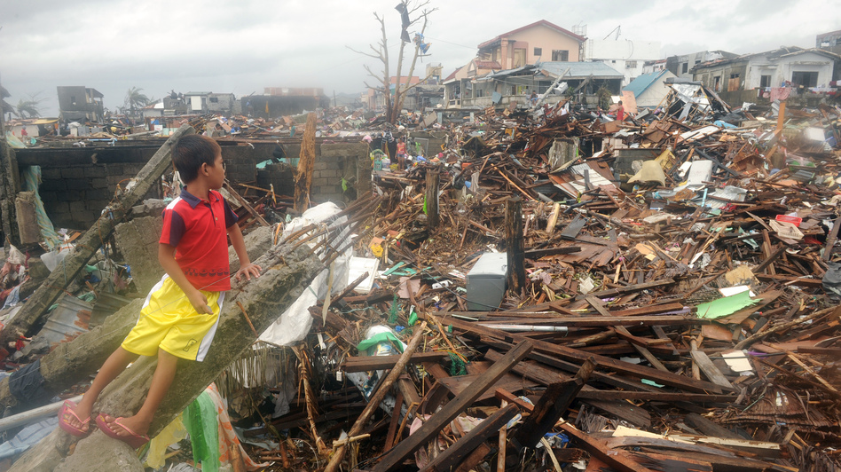 On Tuesday, a boy sat in the debris of destroyed houses in Tacloban, on the eastern Filipino island of Leyte. (Noel Celis /AFP/Getty Images)
