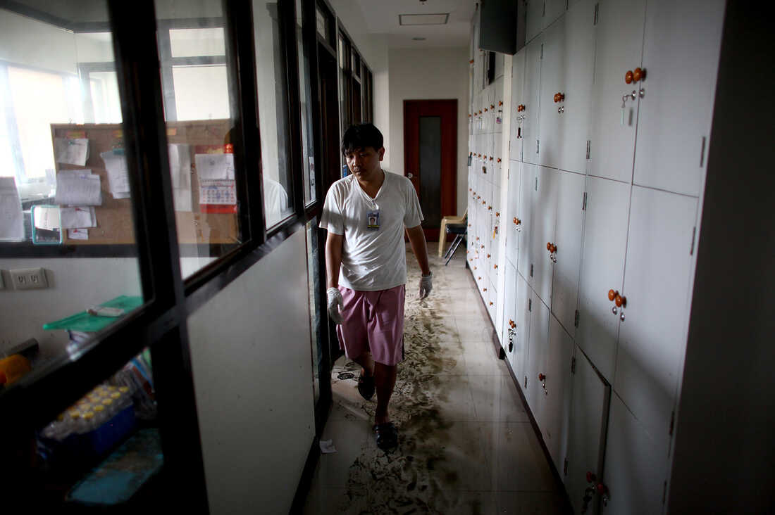 A worker walks through mud and water in the hallways of the Divine Word Hospital in Tacloban, Philippines, on Saturday.
