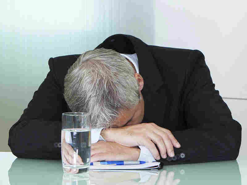 A bored man slumps on a table.