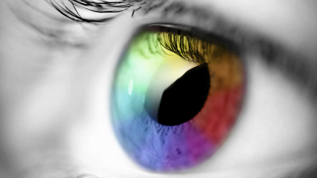 Black and white photo of an eye; the iris is colored in multiple hues.