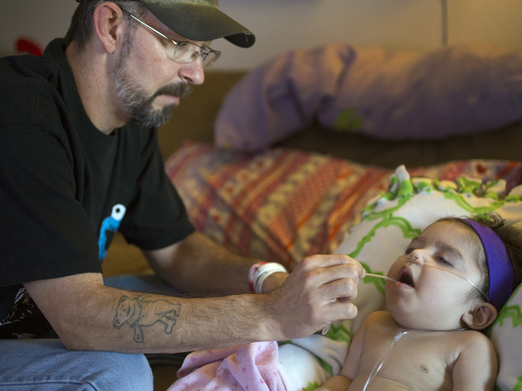 Anthony Shaffer uses a suction device to clear the mouth of Jaylah Donaire-Bechtel, in Harrisburg, Pa. Jaylah has Krabbe disease and can't swallow or speak.