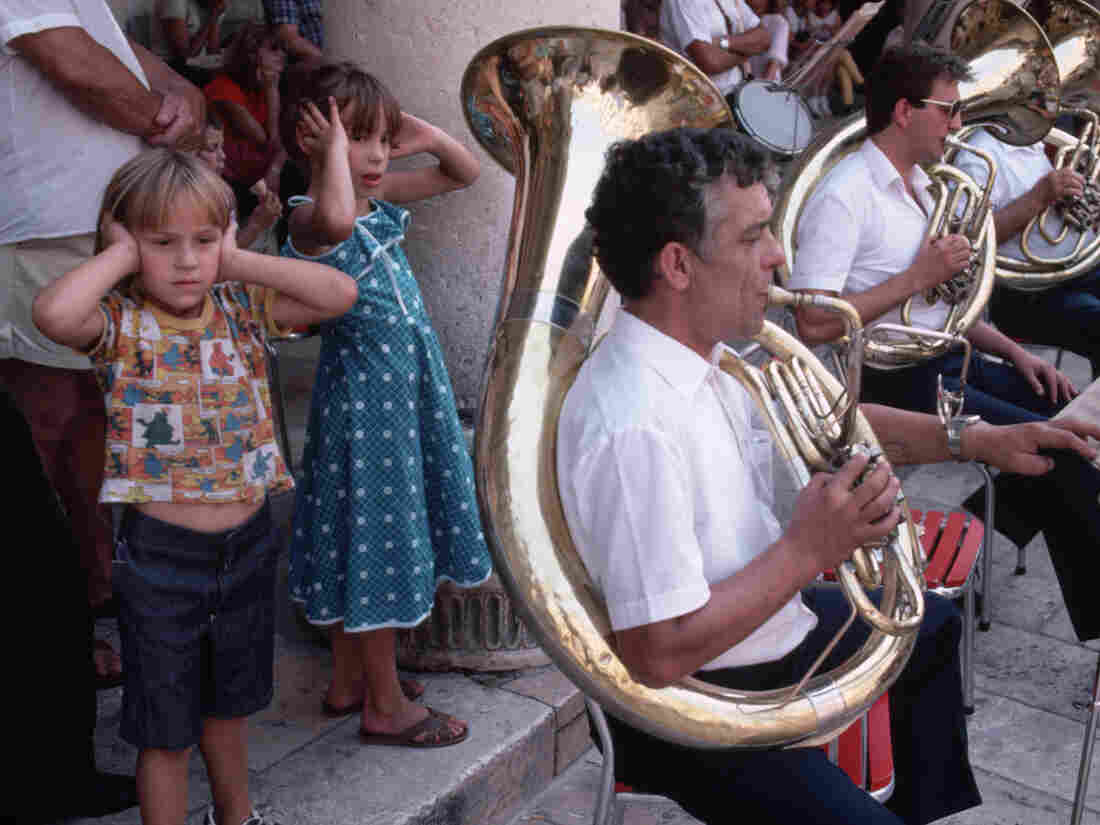 September 1984, Dubrovnik, Croatia --- Small children cover their ears as they stand next to a sousaphone player during a concert played by the Dubrovnik Saturday Band in Dubrovnik, Croatia, Socialist Federal Republic of Yugoslavia.